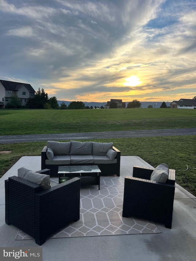 patio terrace at dusk with outdoor lounge area and a lawn