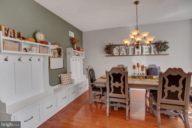 dining room featuring light wood-type flooring, a textured ceiling, and a chandelier