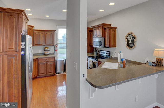 kitchen featuring a kitchen breakfast bar, kitchen peninsula, sink, and appliances with stainless steel finishes