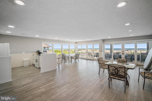 dining area with a textured ceiling and light hardwood / wood-style floors