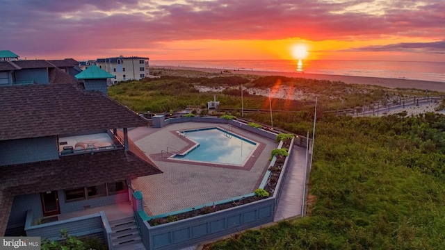 pool at dusk featuring a water view