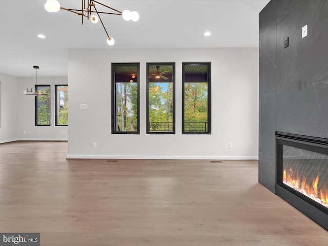 unfurnished living room with a fireplace, hardwood / wood-style floors, and an inviting chandelier