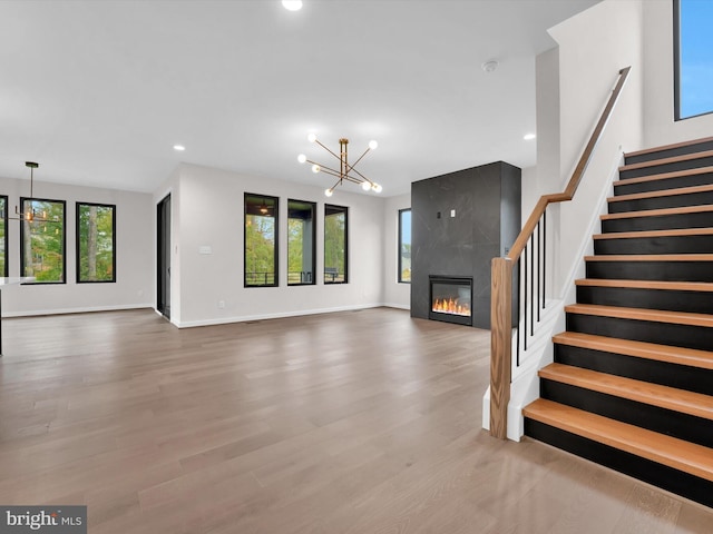 unfurnished living room featuring a fireplace, light hardwood / wood-style flooring, and a notable chandelier