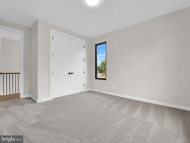 unfurnished bedroom with light colored carpet and a closet