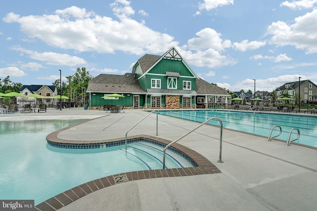 community pool with fence, a patio area, a hot tub, and a residential view