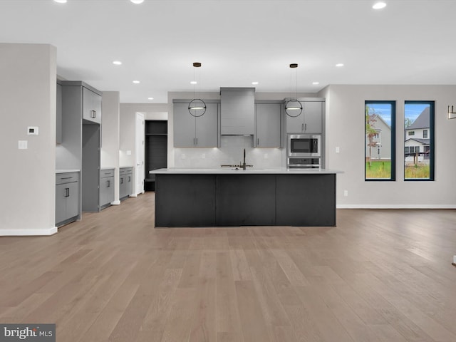 kitchen with pendant lighting, premium range hood, gray cabinets, light hardwood / wood-style floors, and stainless steel appliances