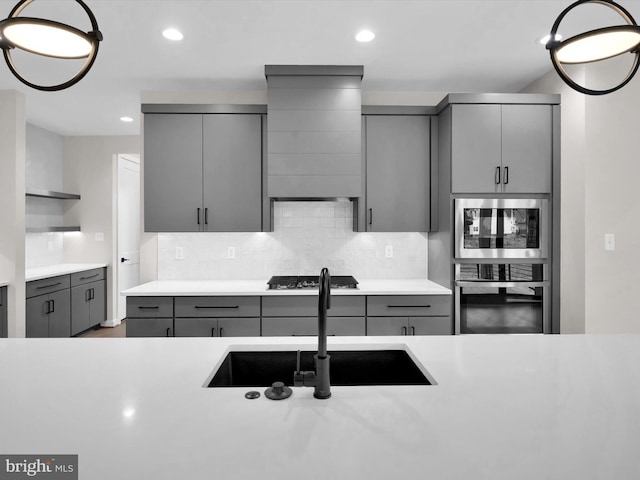 kitchen featuring gray cabinetry, sink, stainless steel appliances, decorative backsplash, and custom exhaust hood