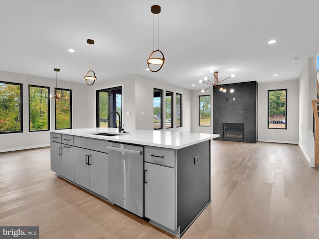 kitchen with pendant lighting, dishwasher, a center island with sink, sink, and gray cabinets