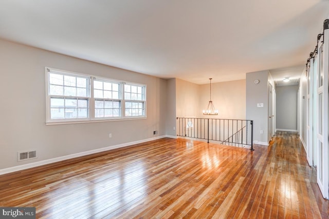 spare room featuring a notable chandelier and wood-type flooring