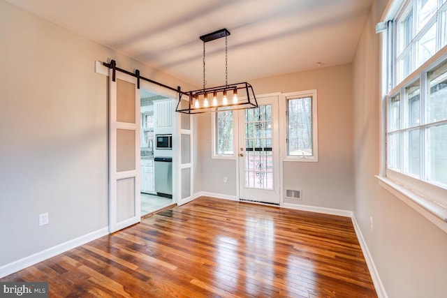 unfurnished dining area featuring hardwood / wood-style floors, a barn door, and plenty of natural light