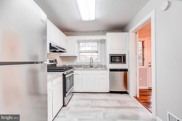 kitchen with stainless steel appliances, a textured ceiling, sink, white cabinets, and tasteful backsplash