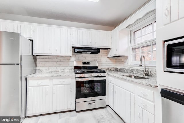 kitchen with sink, white cabinetry, backsplash, exhaust hood, and appliances with stainless steel finishes