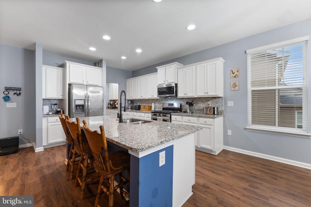 kitchen with sink, white cabinetry, appliances with stainless steel finishes, and an island with sink