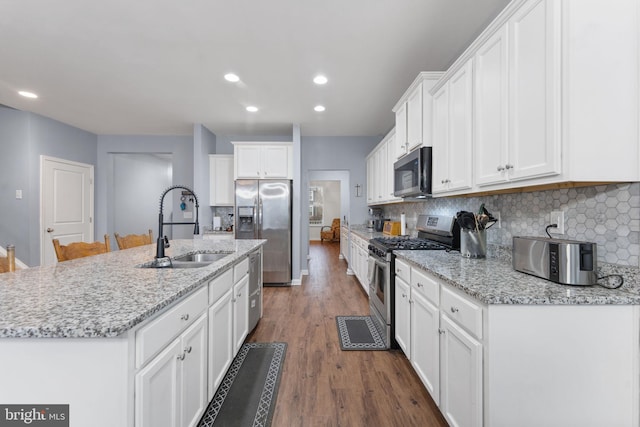 kitchen featuring an island with sink, appliances with stainless steel finishes, sink, and white cabinetry