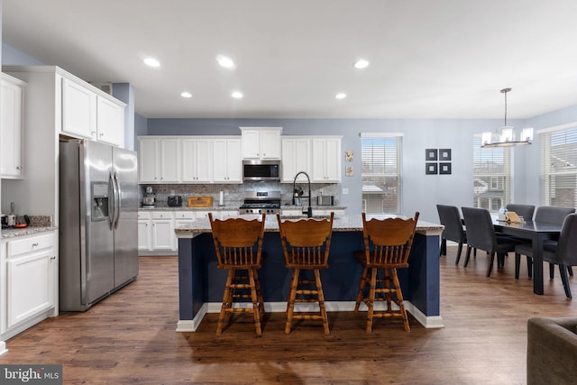 kitchen featuring white cabinetry, light stone countertops, pendant lighting, and stainless steel appliances