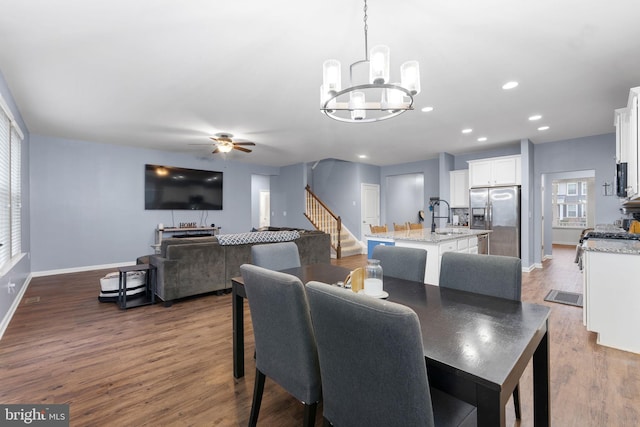 dining room with sink, ceiling fan with notable chandelier, and hardwood / wood-style flooring