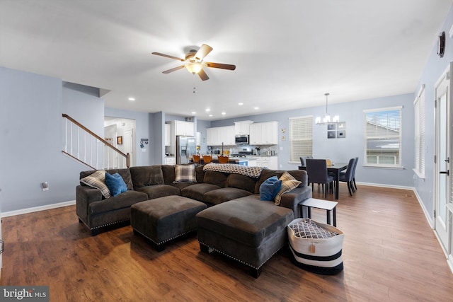 living room featuring ceiling fan with notable chandelier and hardwood / wood-style floors