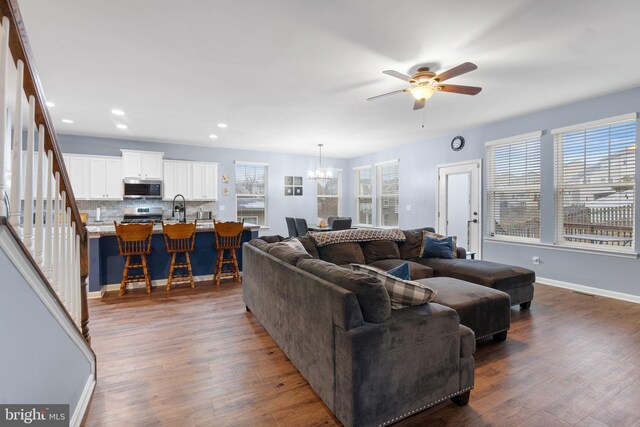 living room with dark wood-type flooring, sink, and ceiling fan with notable chandelier