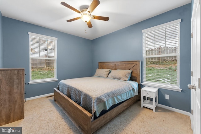 bedroom with ceiling fan, light colored carpet, and multiple windows