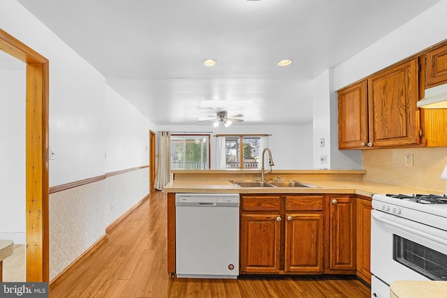 kitchen with ceiling fan, sink, kitchen peninsula, white appliances, and light wood-type flooring