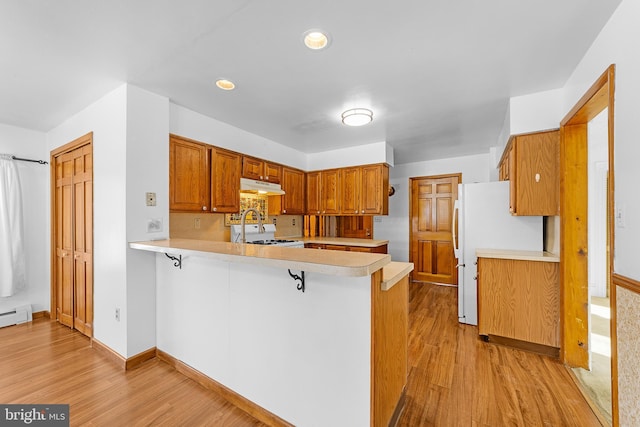 kitchen with kitchen peninsula, a kitchen breakfast bar, stove, and light hardwood / wood-style flooring