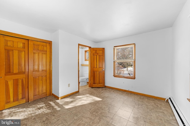 unfurnished bedroom featuring a closet, ensuite bath, and baseboard heating