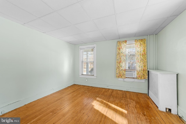 empty room featuring light hardwood / wood-style flooring, cooling unit, and plenty of natural light