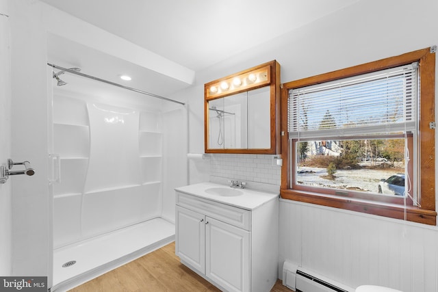 bathroom with decorative backsplash, walk in shower, vanity, a baseboard radiator, and hardwood / wood-style floors