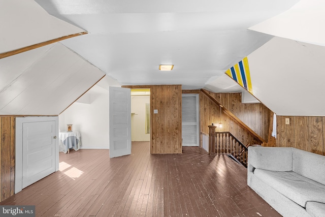 additional living space with hardwood / wood-style flooring, lofted ceiling, and wooden walls