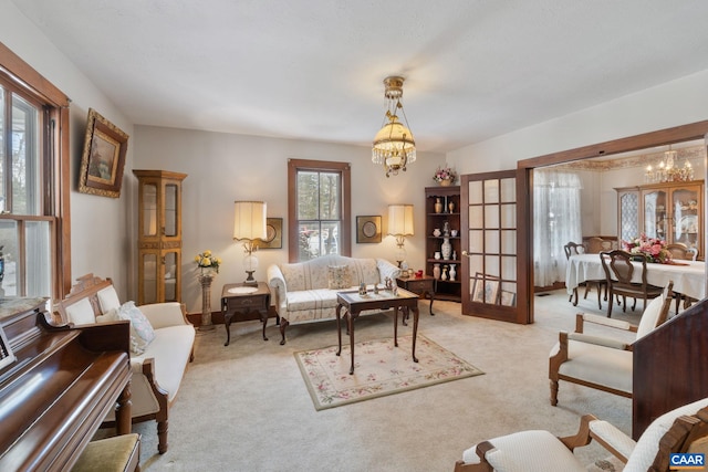 living room featuring light colored carpet, french doors, and an inviting chandelier