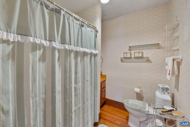 bathroom with hardwood / wood-style flooring, vanity, toilet, and walk in shower