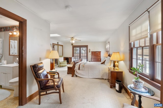 bedroom featuring ceiling fan, sink, connected bathroom, and light carpet