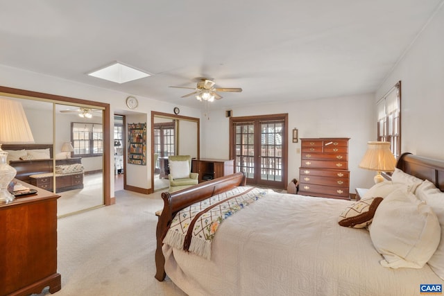 bedroom featuring light carpet, french doors, a skylight, and ceiling fan