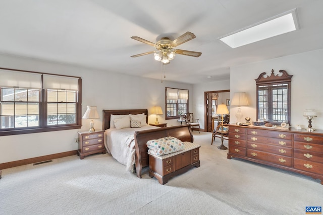 bedroom featuring light carpet, a skylight, and ceiling fan