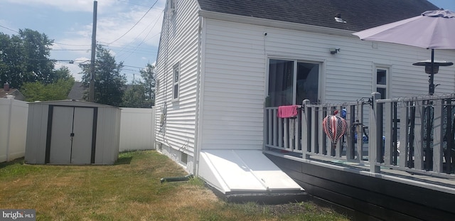 view of side of property with a storage unit, a deck, and a yard