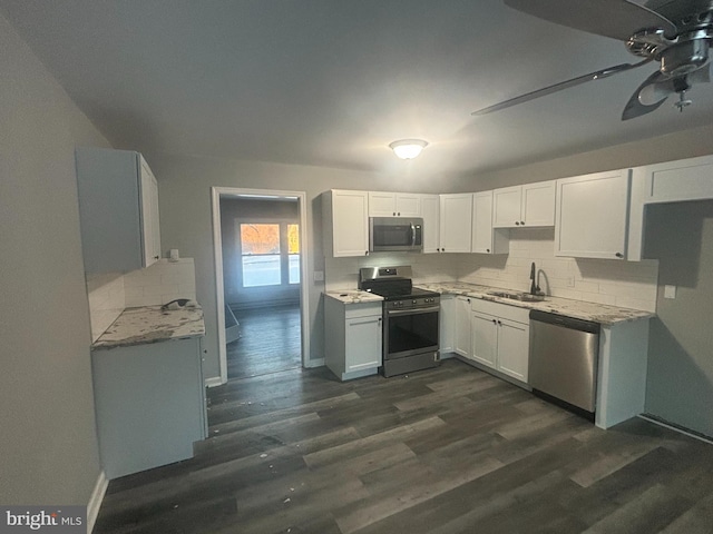 kitchen with dark wood-type flooring, sink, decorative backsplash, white cabinetry, and stainless steel appliances