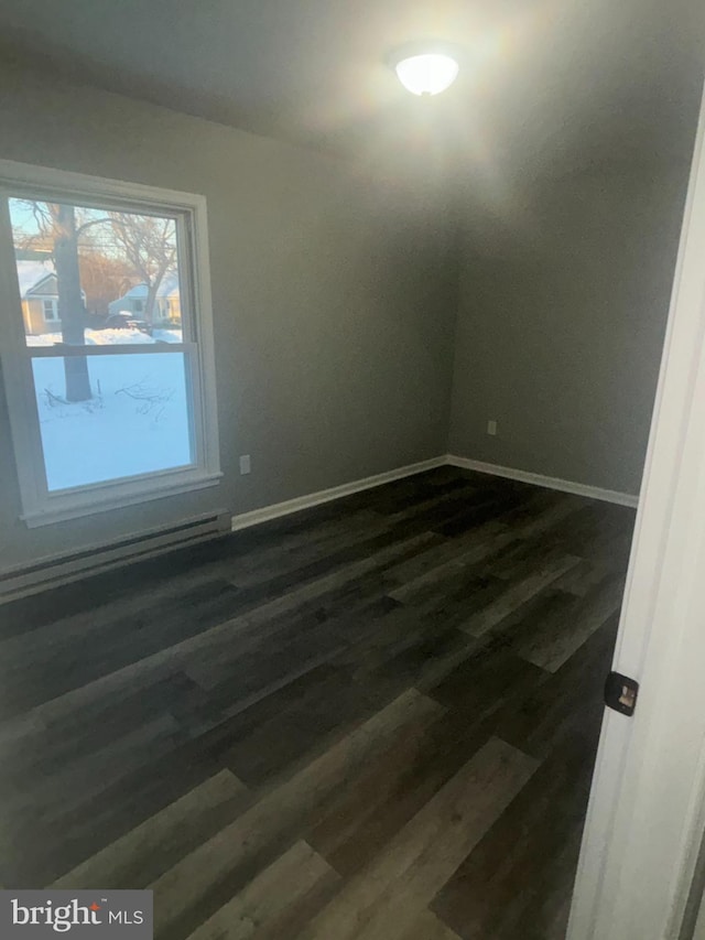 spare room featuring a baseboard radiator and dark hardwood / wood-style floors