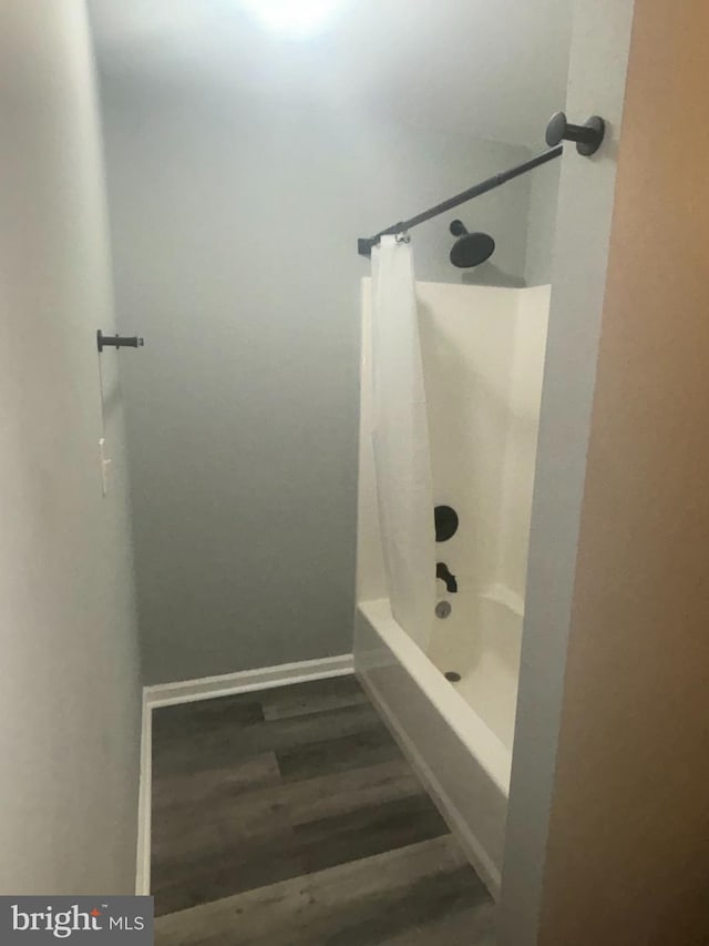 bathroom with wood-type flooring and washtub / shower combination