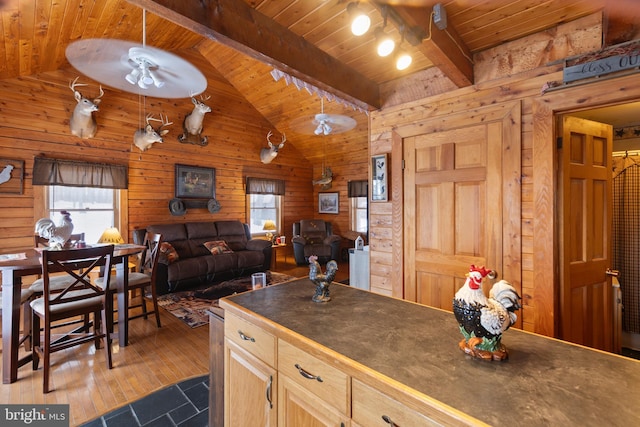 kitchen with wood walls, light brown cabinetry, wood ceiling, and decorative light fixtures