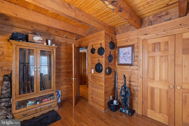 interior space featuring beam ceiling, wooden walls, and wood-type flooring