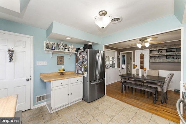 kitchen with white cabinets, ceiling fan, light tile patterned floors, and stainless steel refrigerator