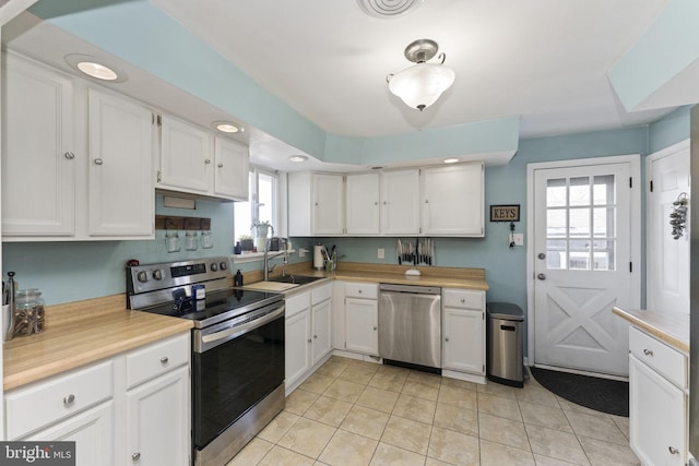 kitchen featuring sink, white cabinetry, stainless steel appliances, and light tile patterned floors