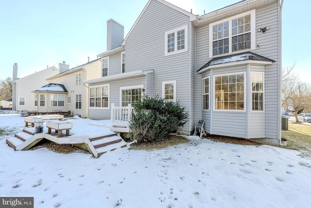 snow covered house with central AC unit and a deck