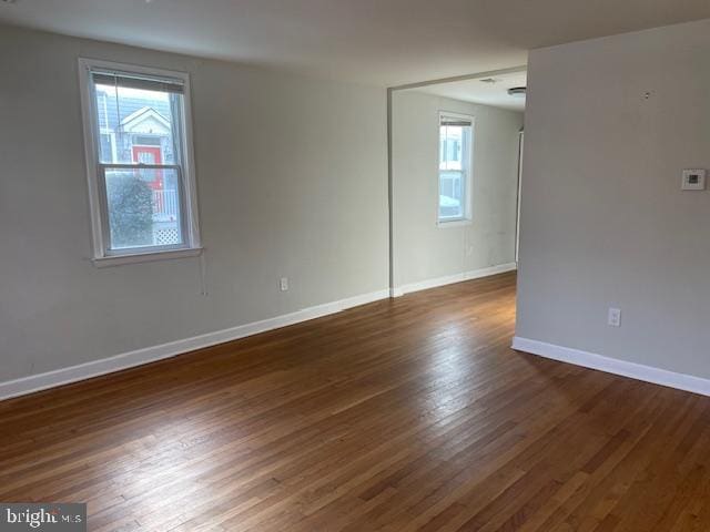 empty room with dark wood-type flooring and a wealth of natural light