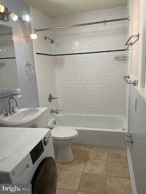 full bathroom with washer / clothes dryer, sink, tiled shower / bath combo, and tile patterned flooring