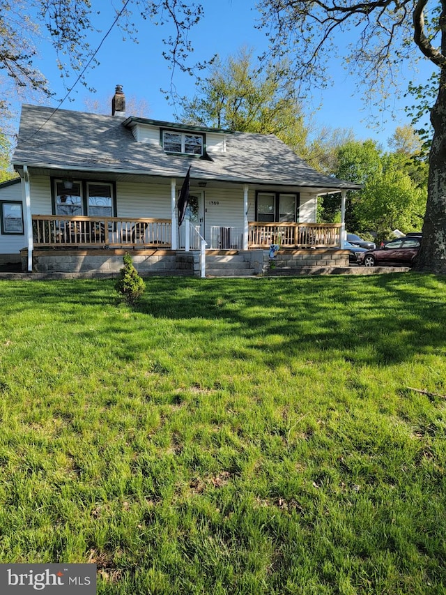 back of property featuring covered porch and a lawn