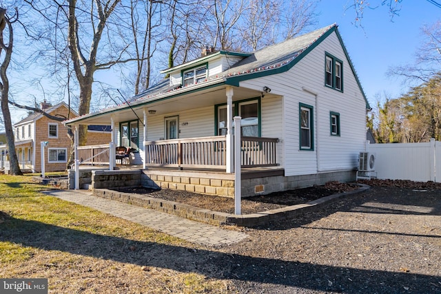 view of front of property with ac unit, a front yard, and a porch