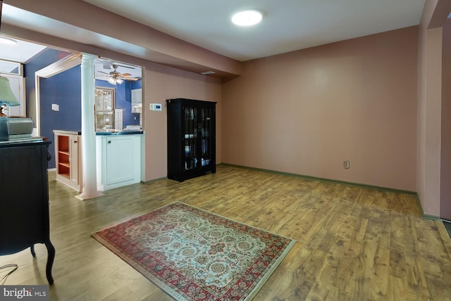 living room featuring ornate columns, ceiling fan, and light wood-type flooring