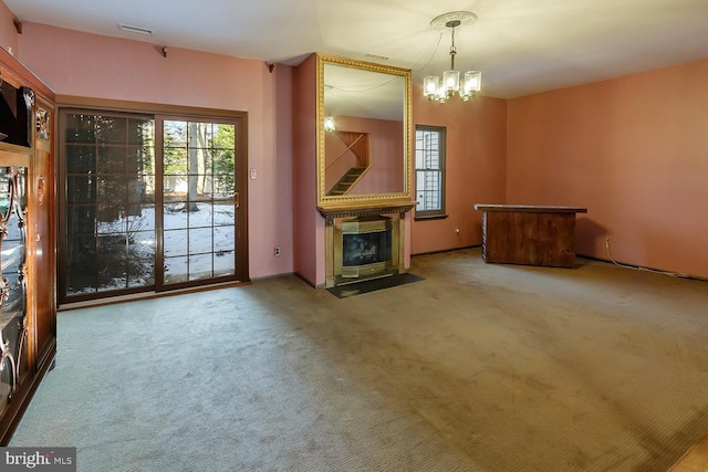 unfurnished living room with a healthy amount of sunlight, carpet floors, and a notable chandelier