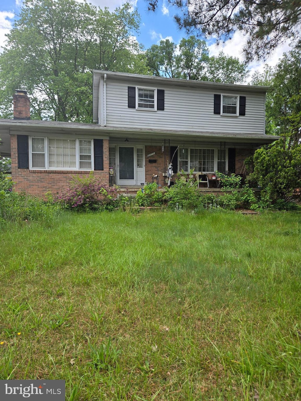 9517 Nordic Dr, Lanham, MD 20706 - traditional-style home with covered porch, brick siding, and a chimney